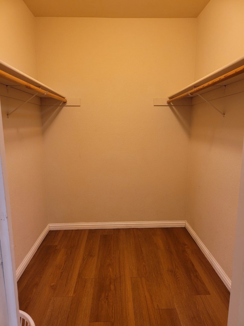 A closet with two wooden shelves and one is open.