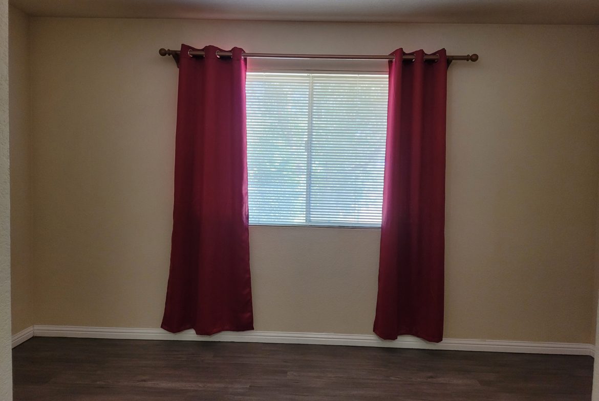 A room with two windows and a wooden floor.