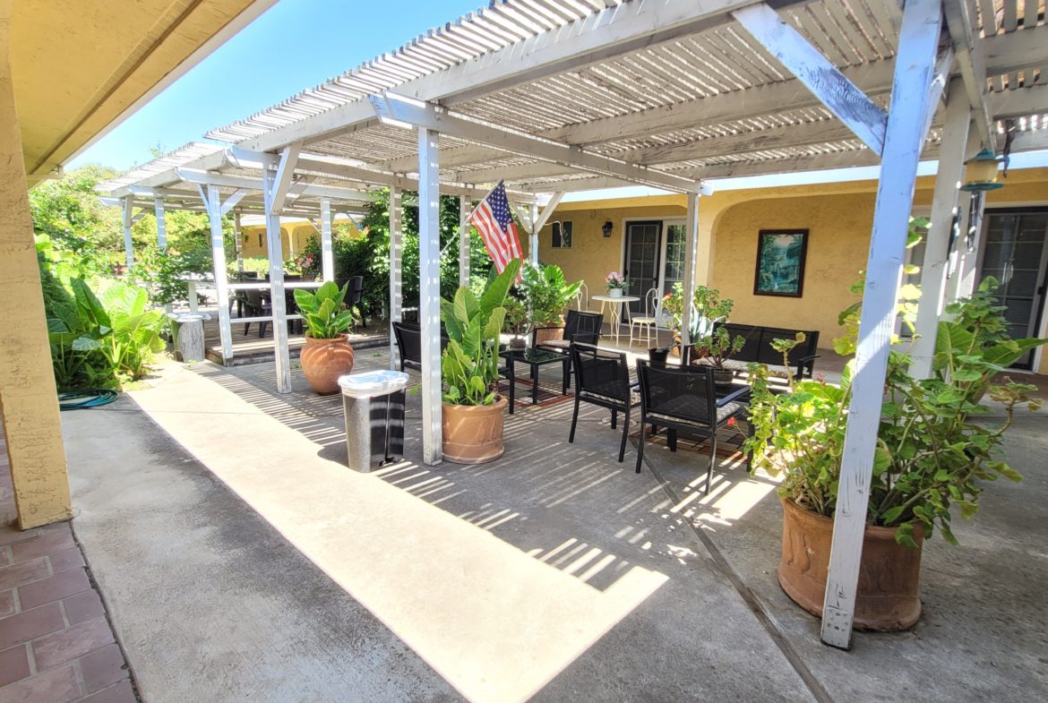 A patio with tables and chairs under an awning.