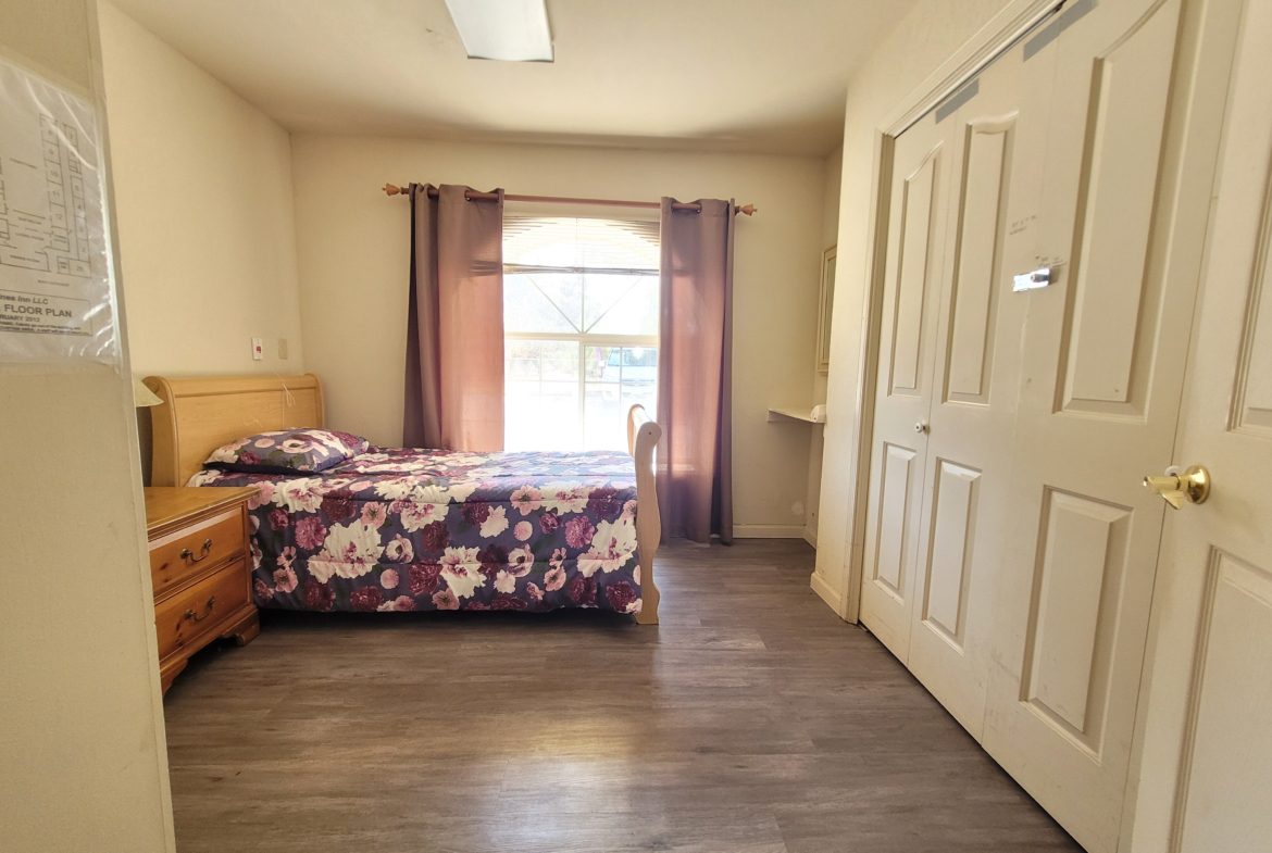 A bedroom with a bed, dresser and window.