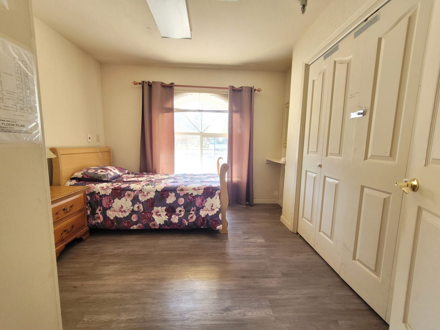 A bedroom with a bed, dresser and window.