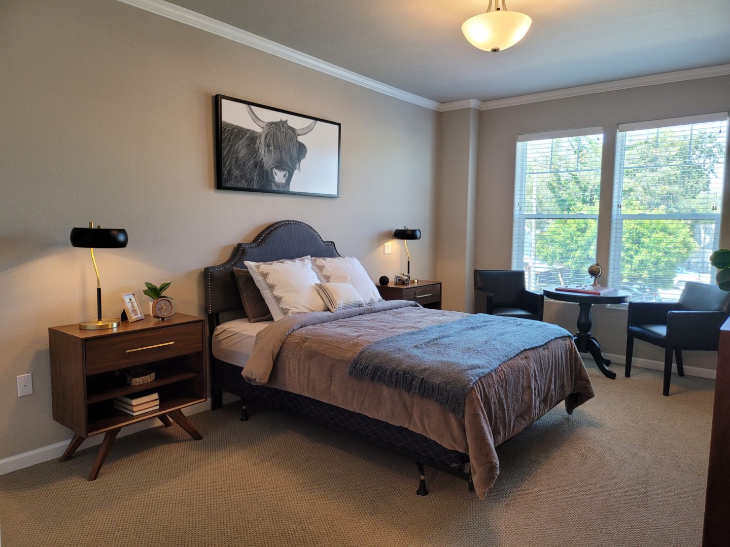 A bedroom with a bed, nightstand and desk.