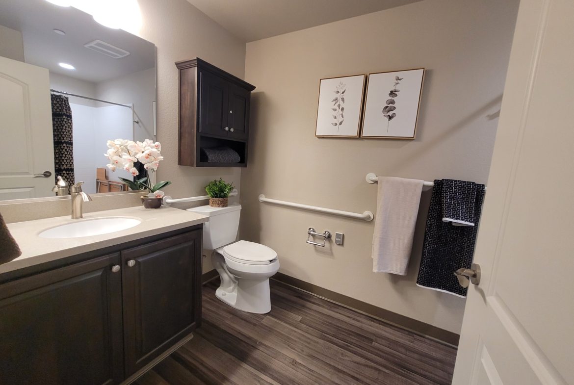 A bathroom with wood floors and white fixtures.