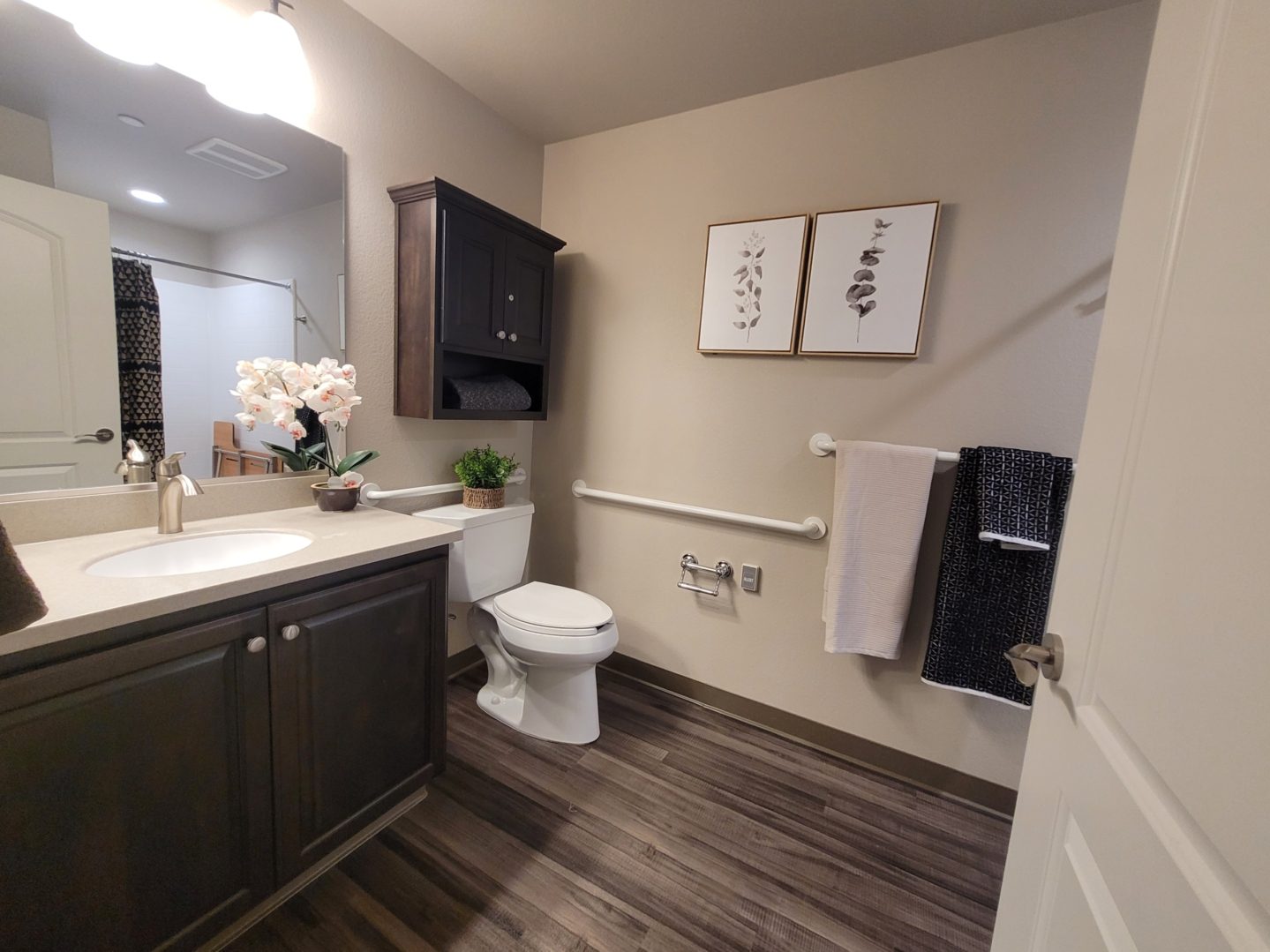 A bathroom with wood floors and white fixtures.