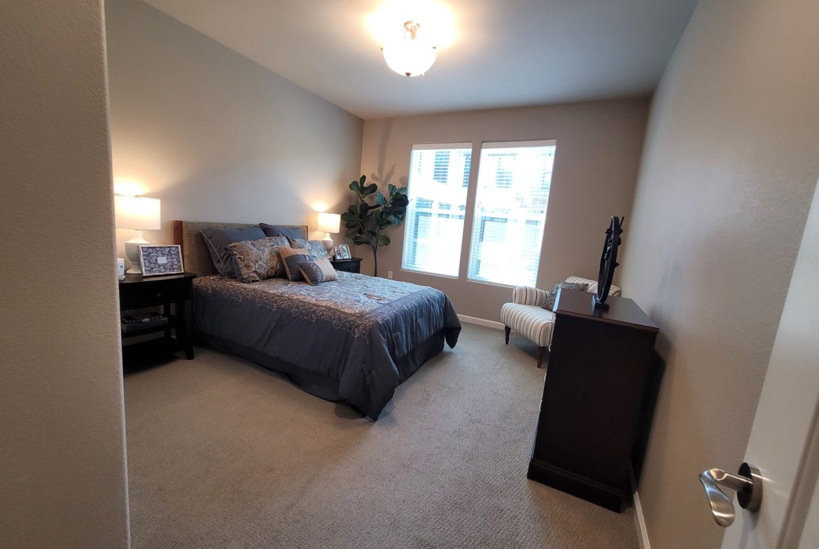 A bedroom with a bed, dresser and window.