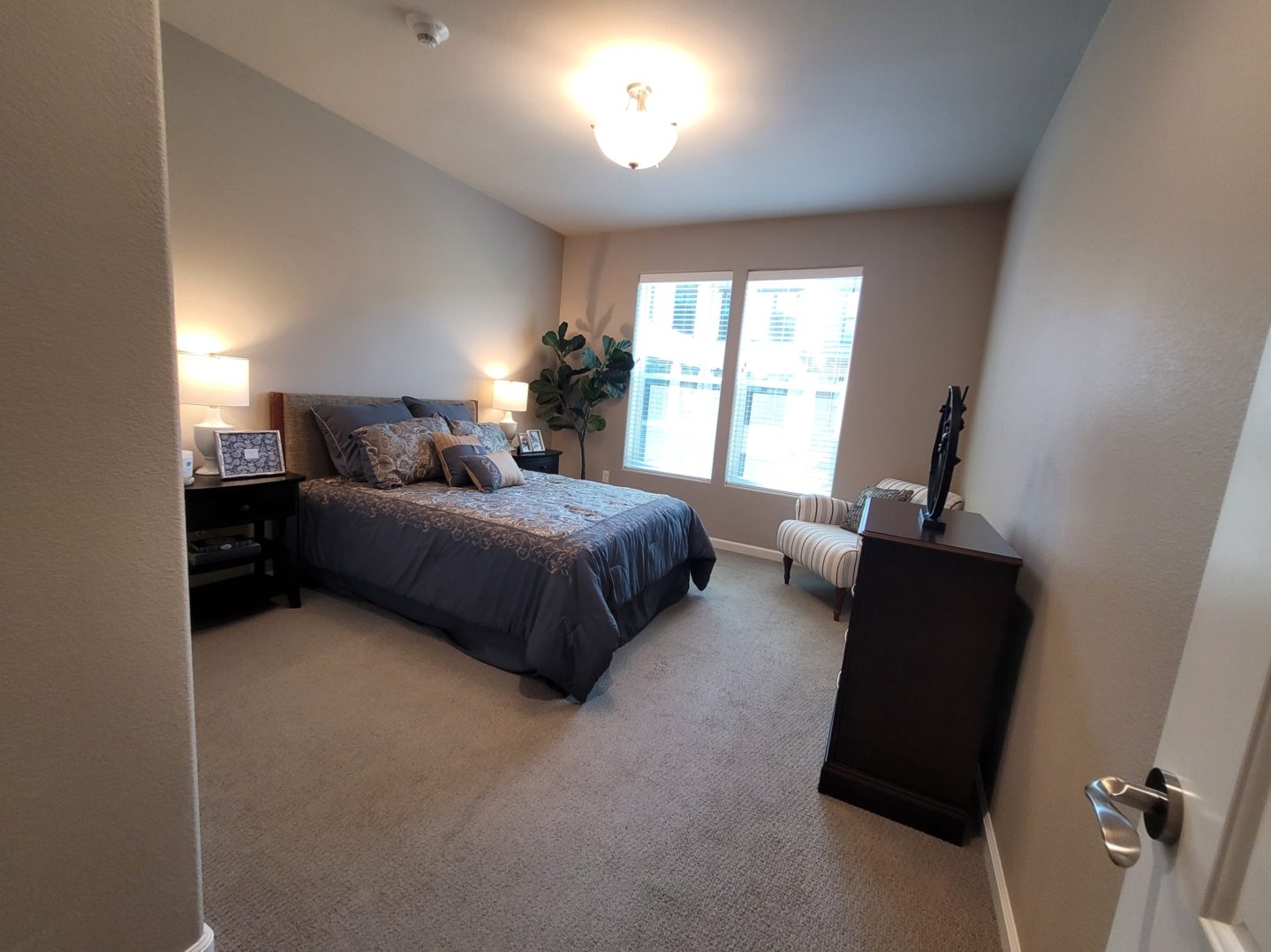 A bedroom with a bed, dresser and window.