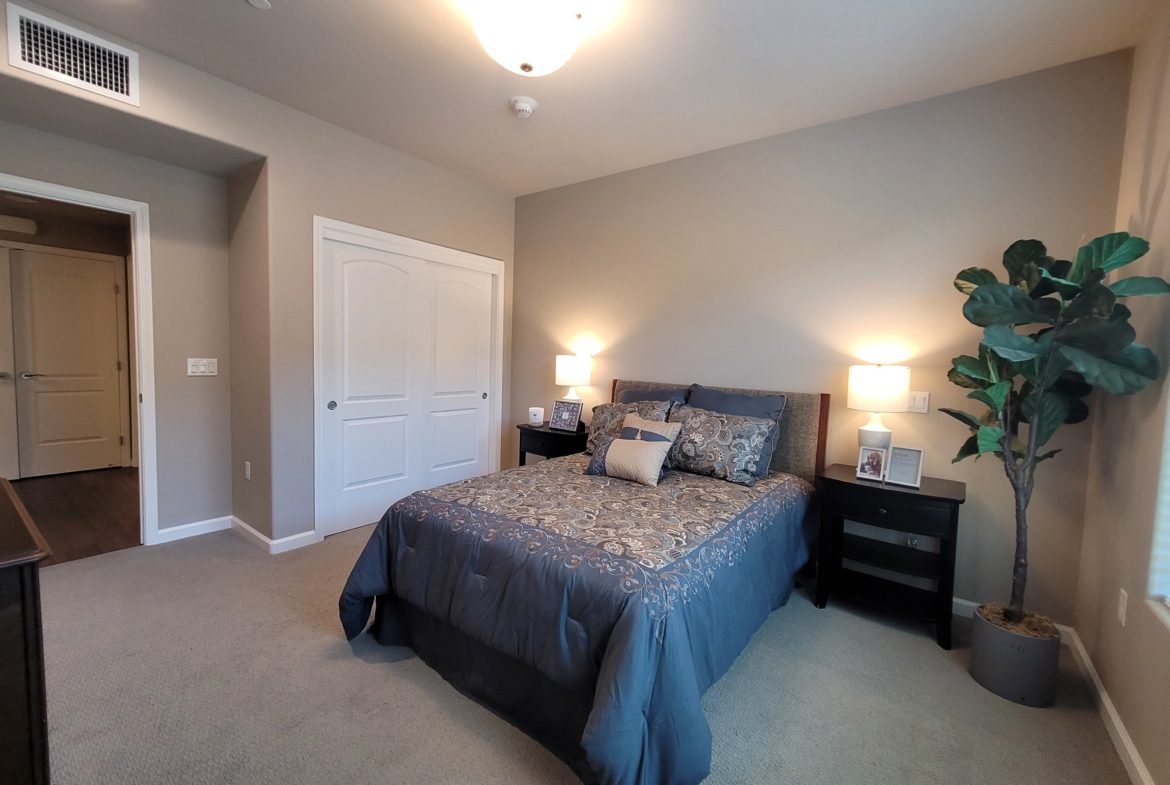 A bedroom with a bed, nightstand and dresser.