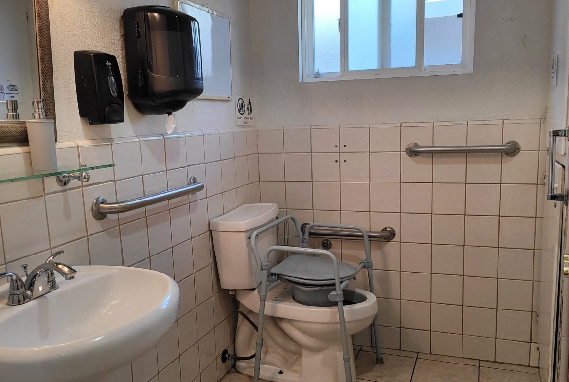 A bathroom with a sink, toilet and mirror.