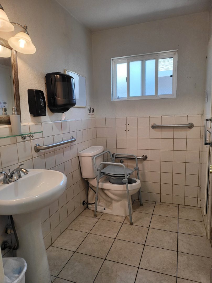 A bathroom with a sink, toilet and mirror.