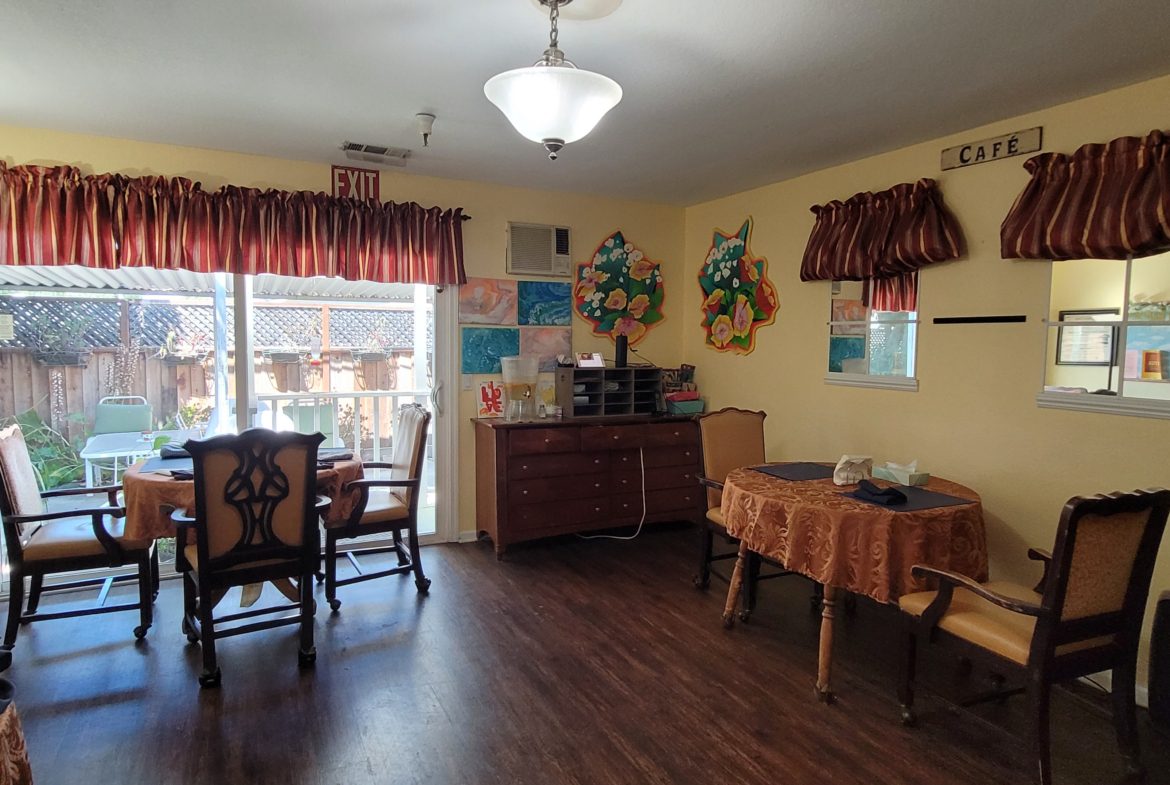 A room with wooden floors and walls, a table and chairs.