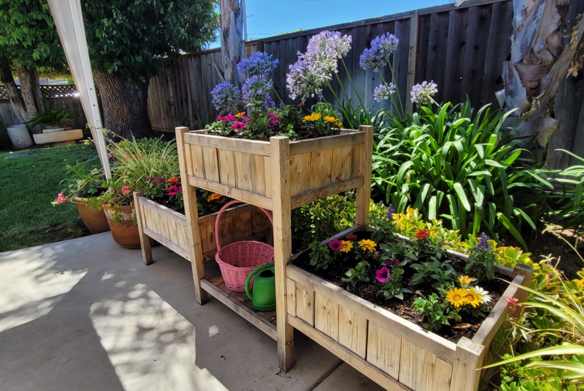 A couple of wooden planters filled with flowers.