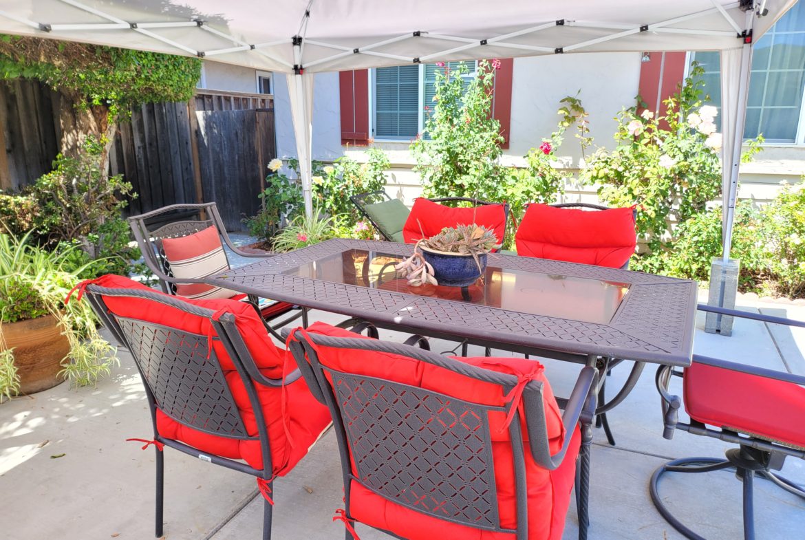 A table and chairs set up outside under an umbrella.