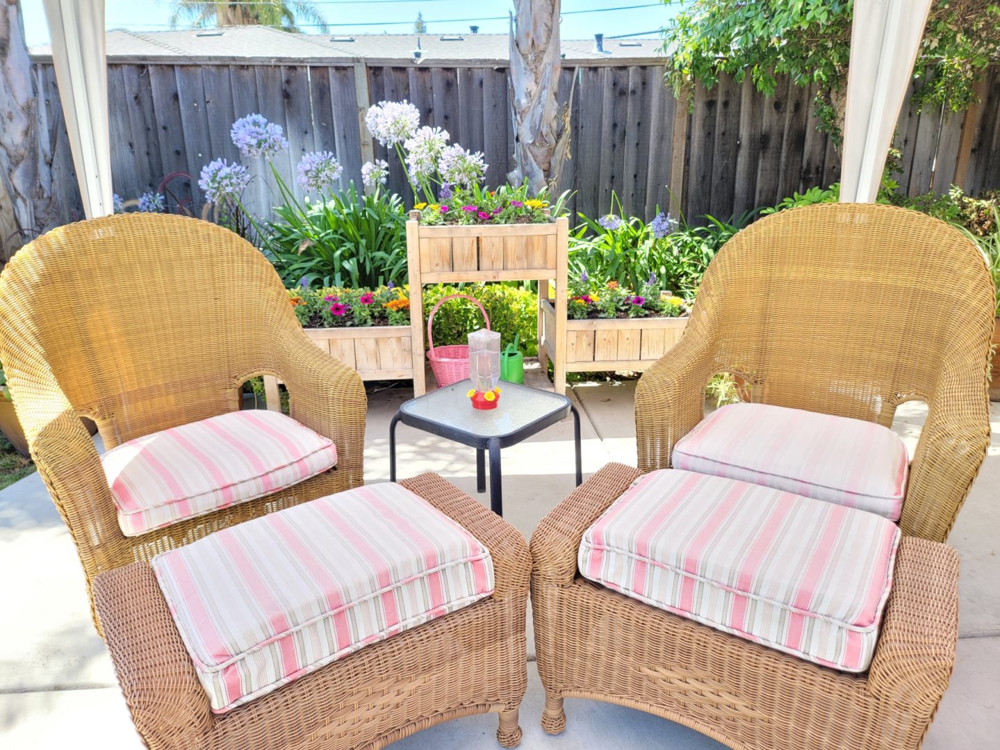 A patio with four chairs and ottomans on the ground.