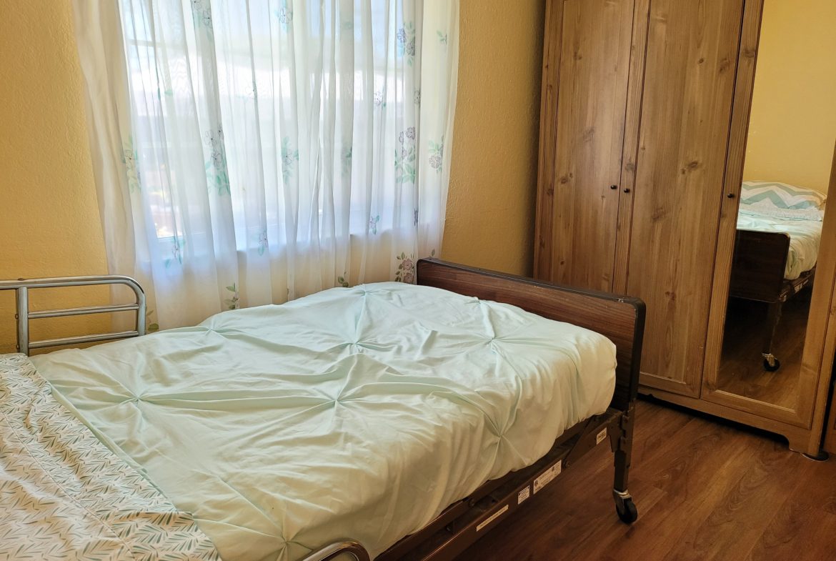 A bed room with a wooden floor and a white curtain