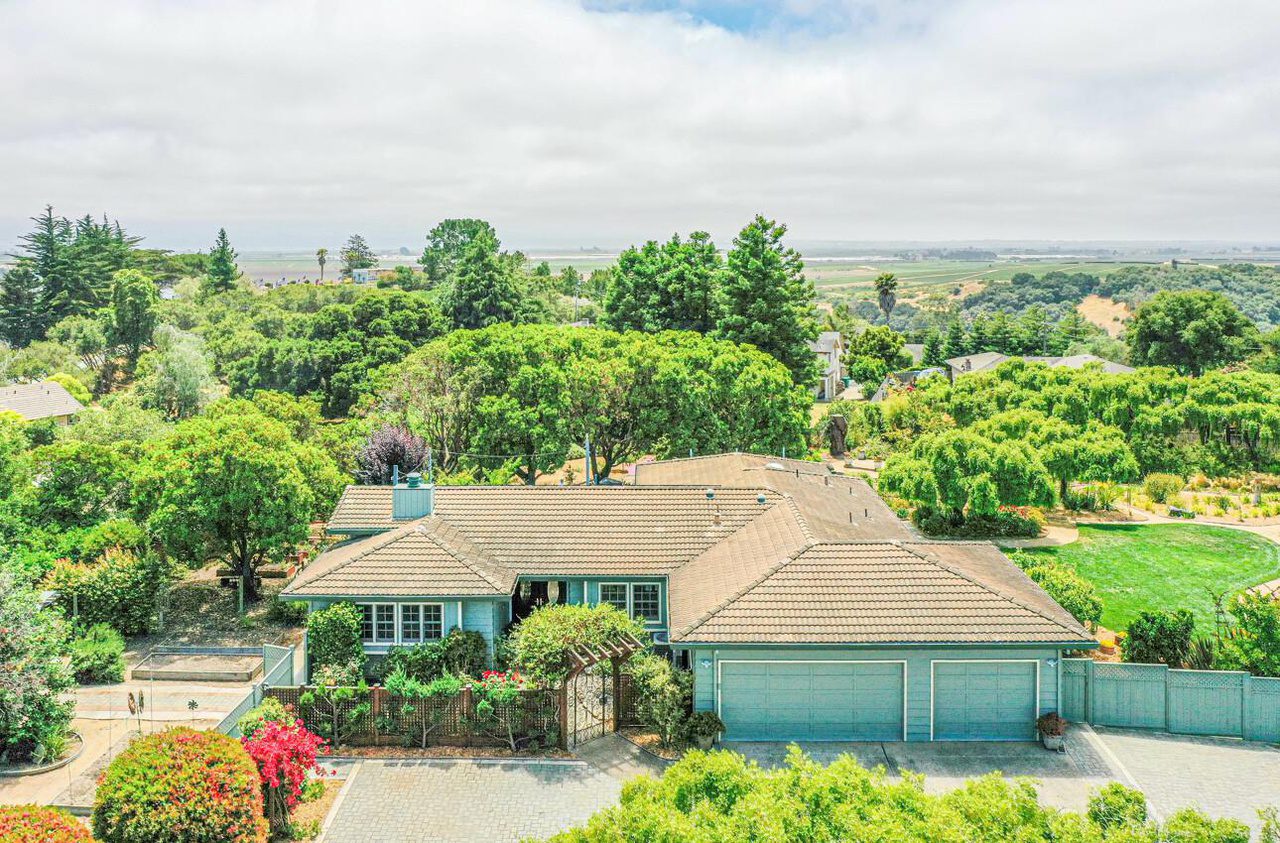 A large blue house with trees in the background