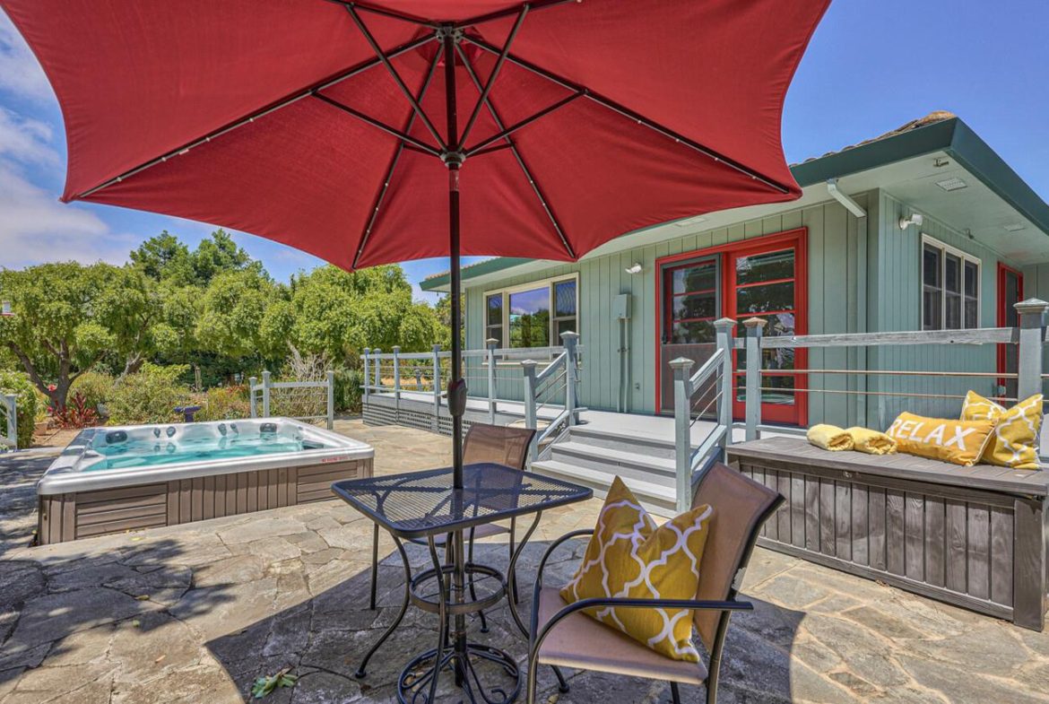 A patio with an umbrella and chairs in the middle of it