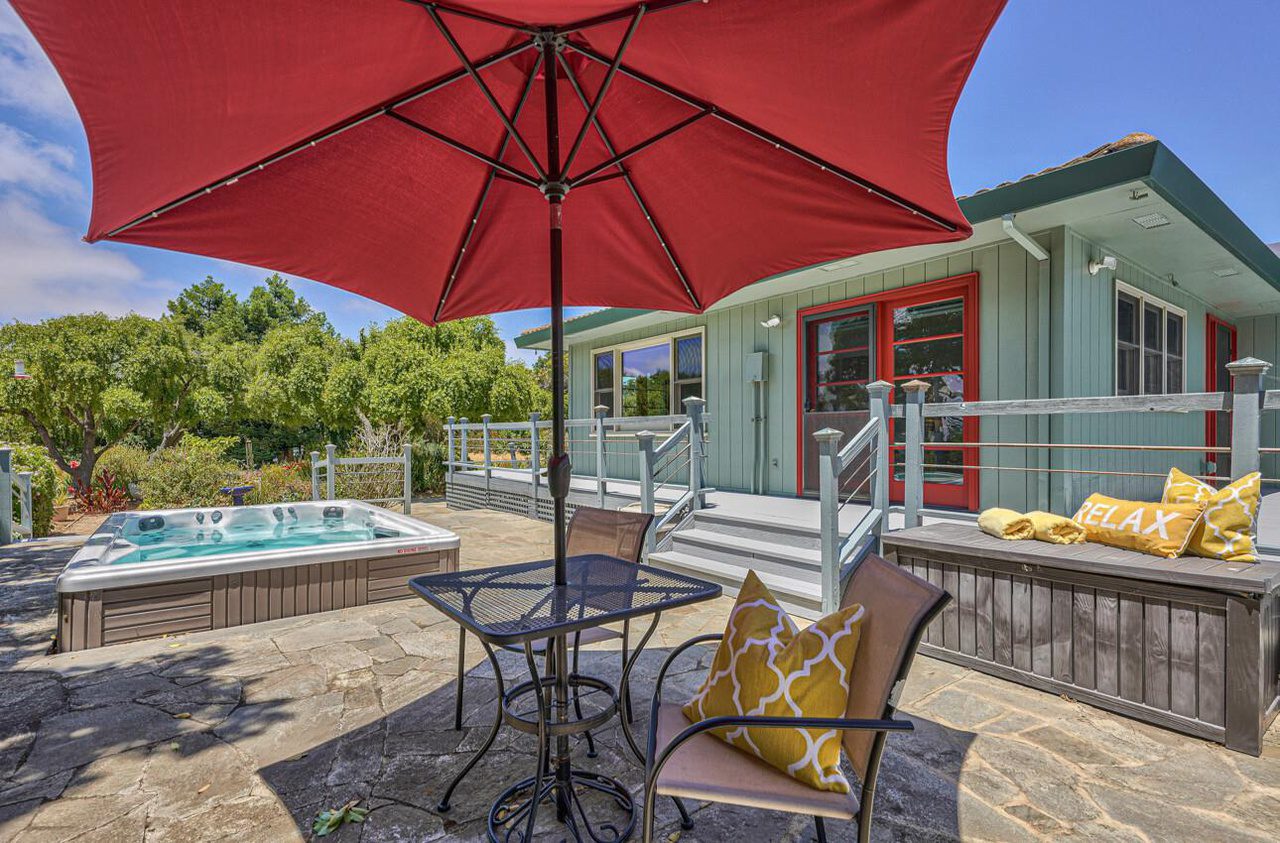 A patio with an umbrella and chairs in the middle of it