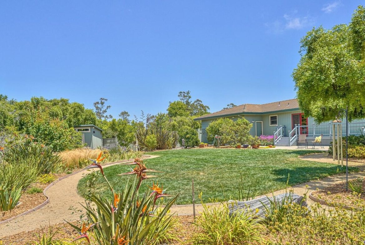 A yard with grass and flowers in the foreground.