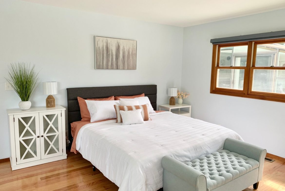 A bedroom with a bed, nightstand and window.