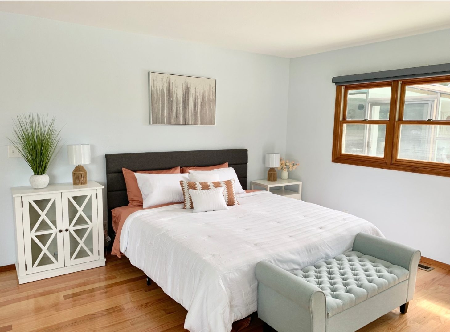 A bedroom with a bed, nightstand and window.