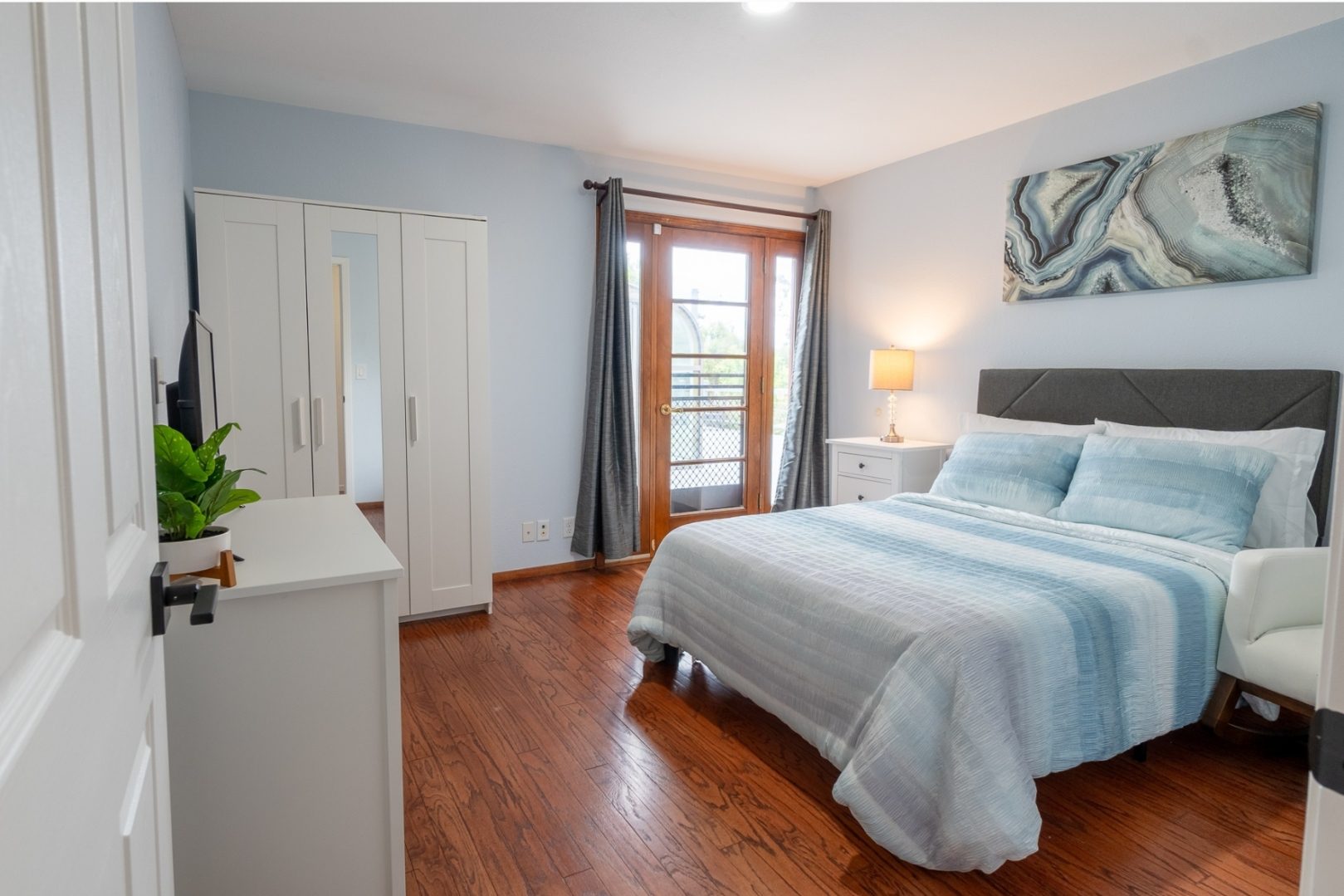 A bedroom with a bed, dresser and window.