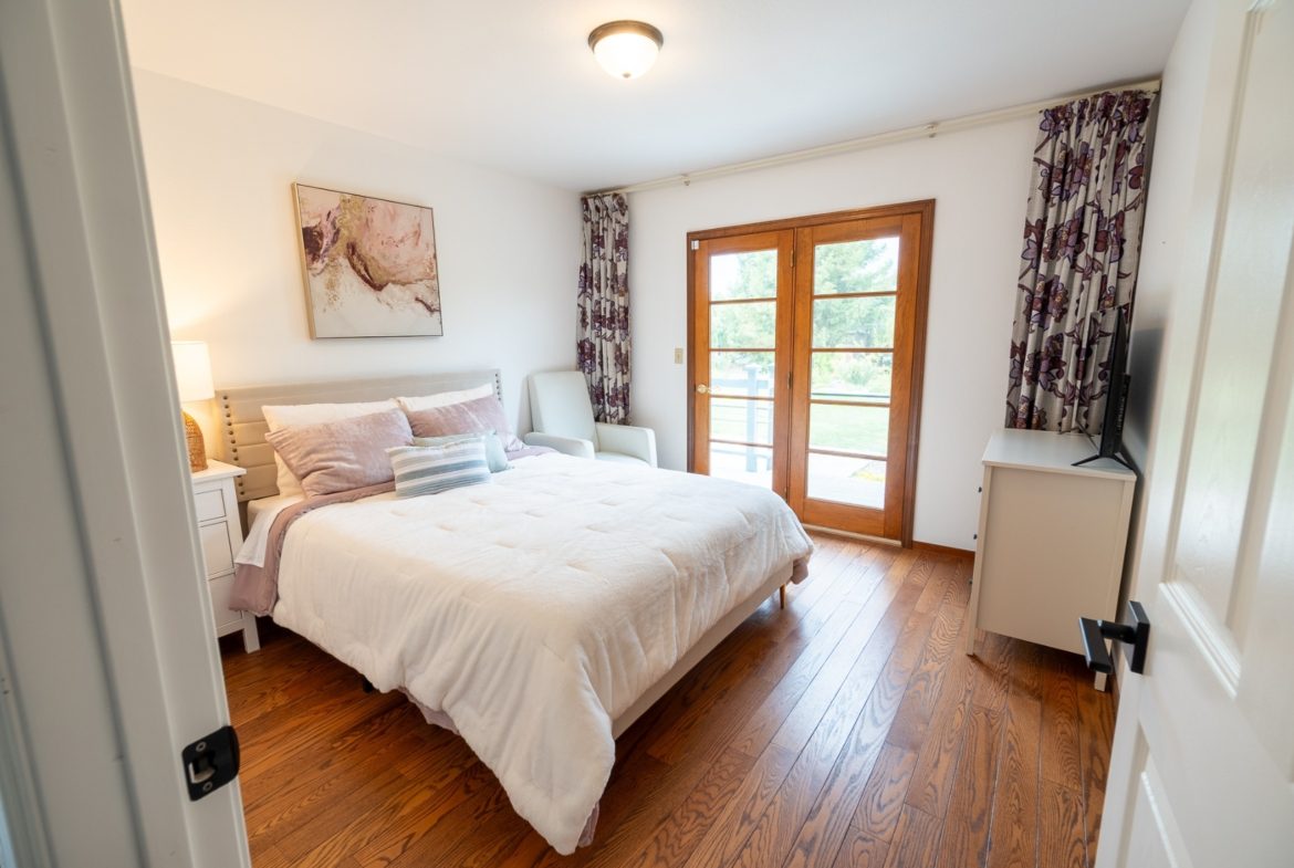 A bedroom with a bed, dresser and window.