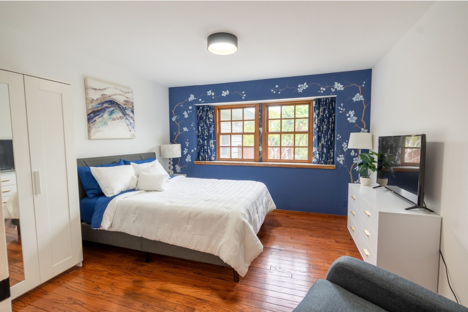 A bedroom with blue walls and white bedding.