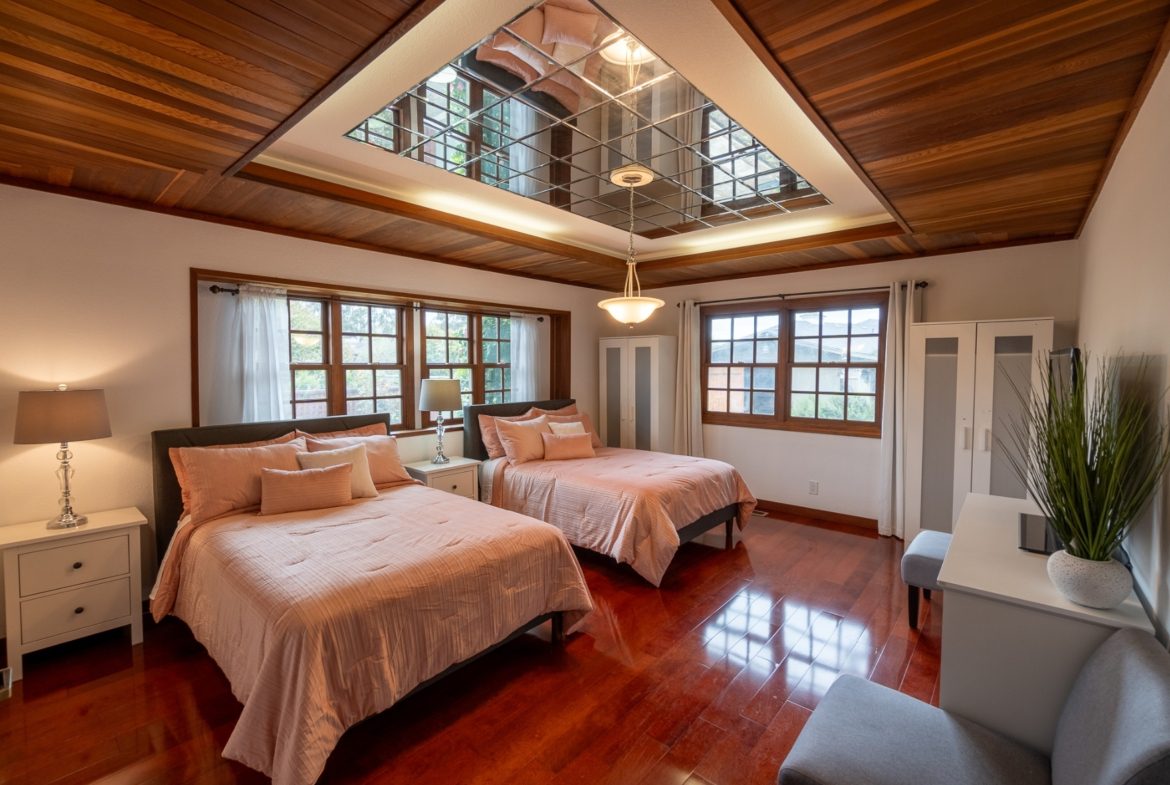 A bedroom with two beds and wooden floors