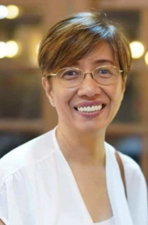 Smiling woman wearing glasses and white shirt.
