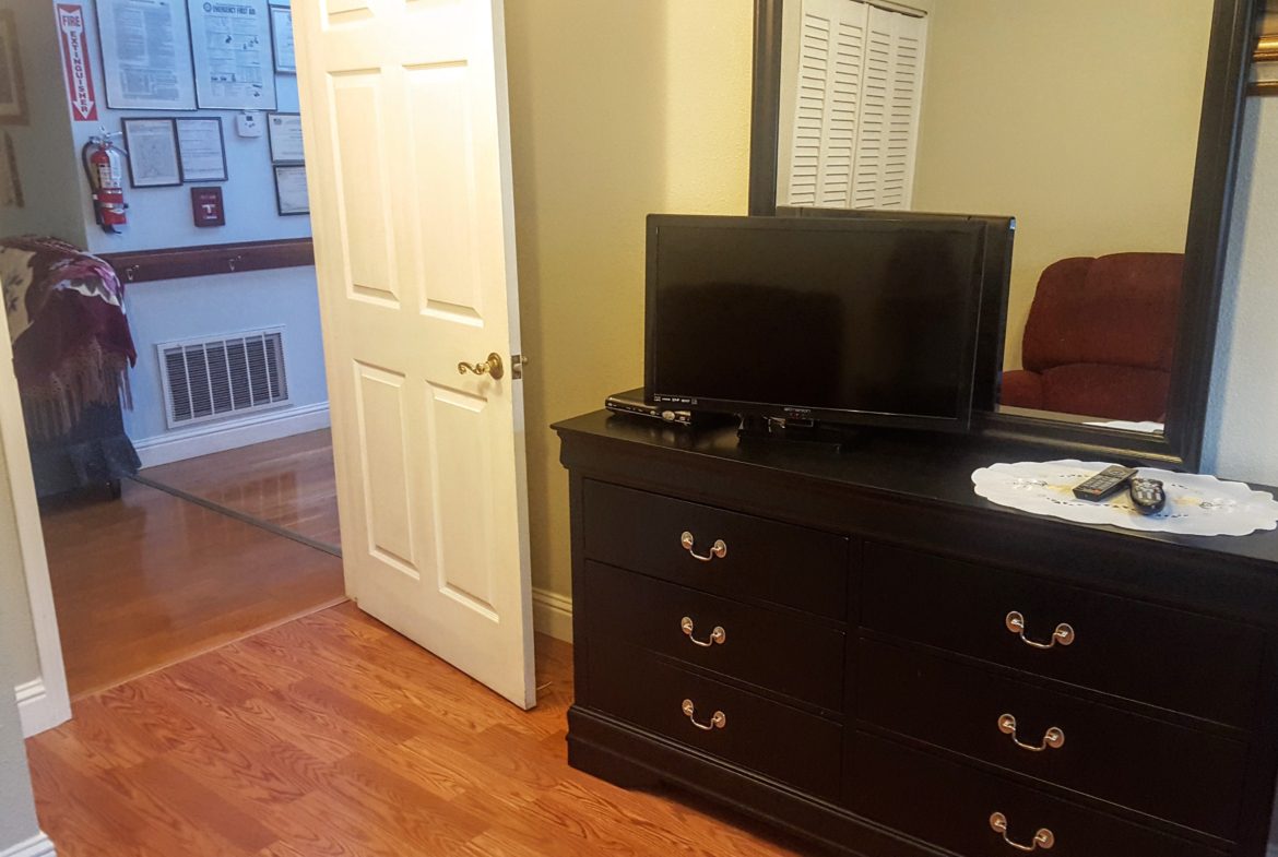Bedroom dresser with TV and mirror.