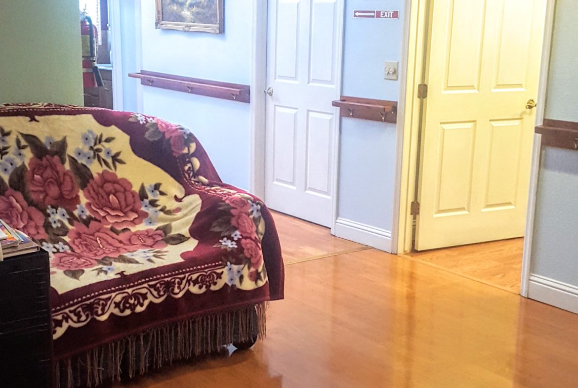 Hallway with floral couch and wooden floor.