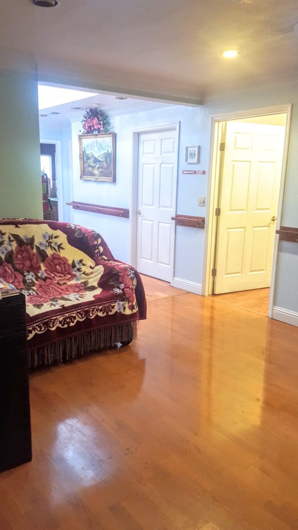 Hallway with floral couch and wooden floor.