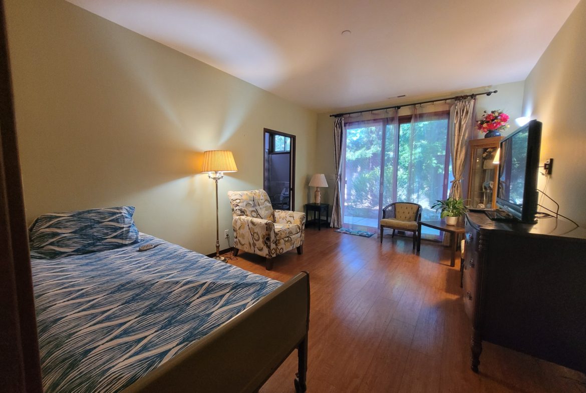 Bedroom with bed, chairs, and large window.