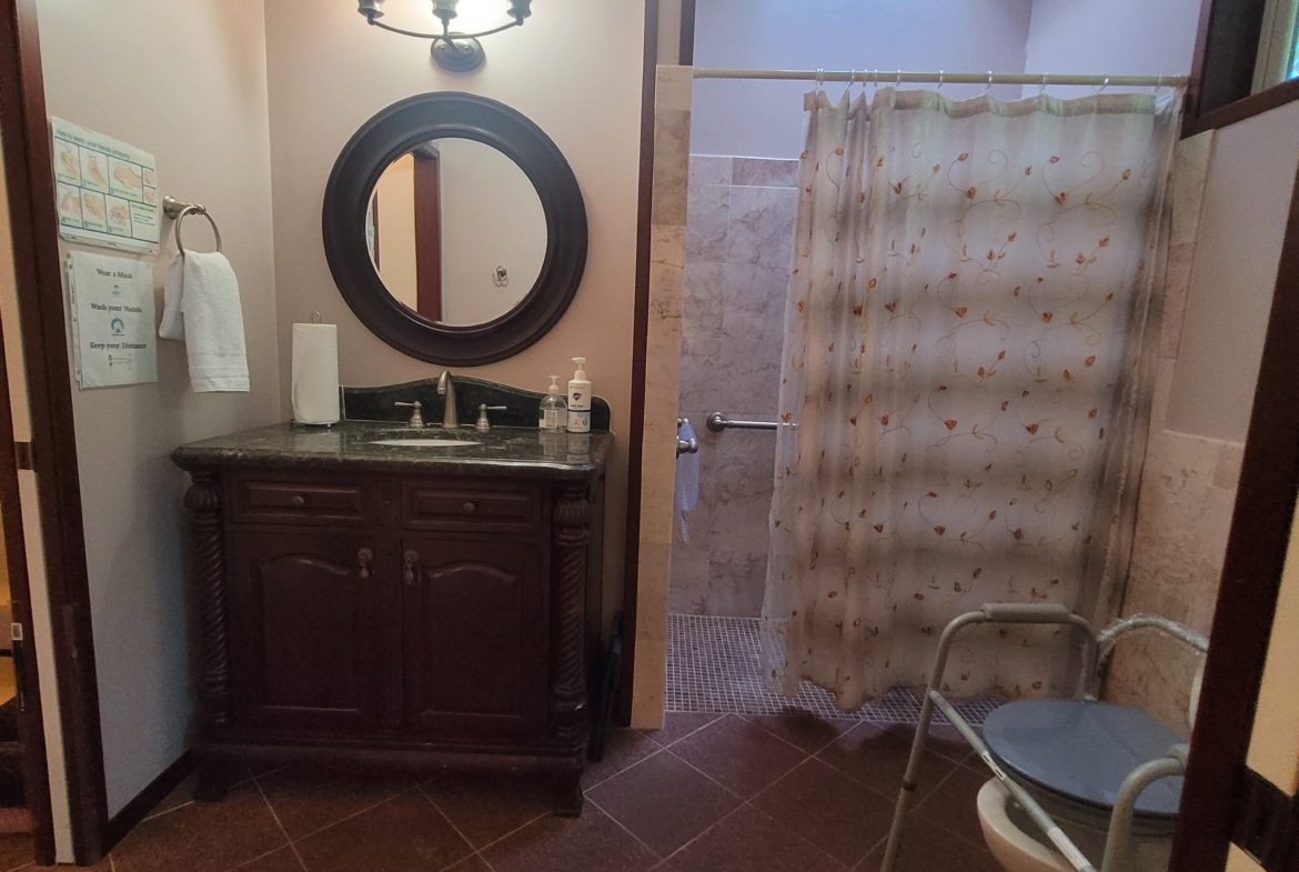 Bathroom with vanity, shower, and toilet seat.