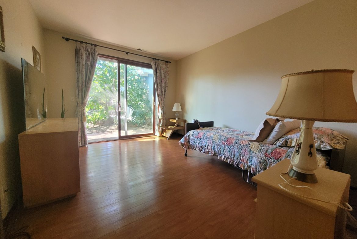 Bedroom with large window and wooden floor.