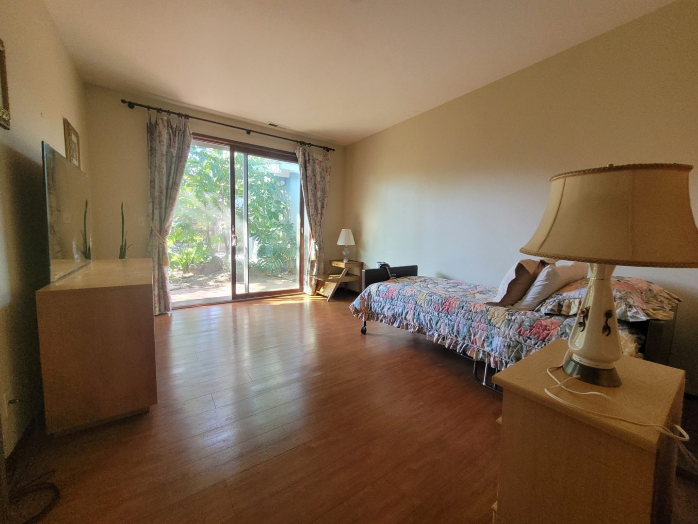 Bedroom with large window and wooden floor.