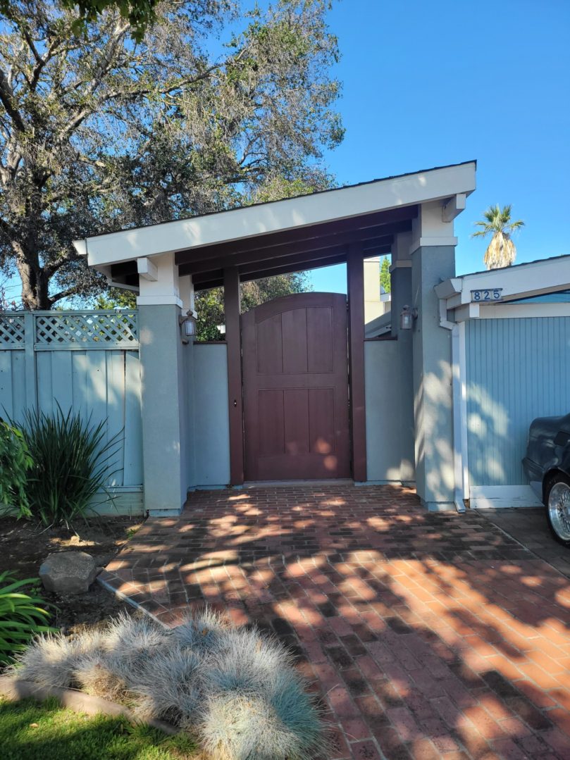 Wooden gate with brick pathway and trees.