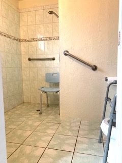 Accessible bathroom with shower chair and rails.
