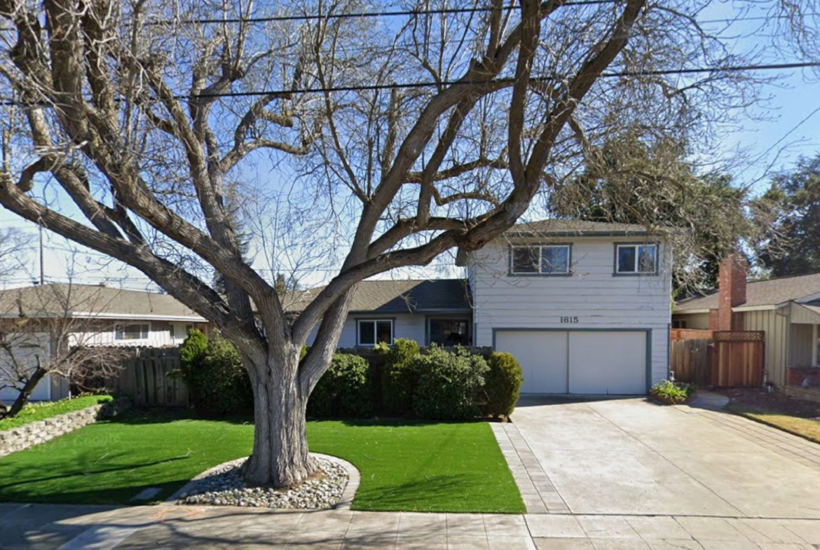 Suburban house with large tree in front.