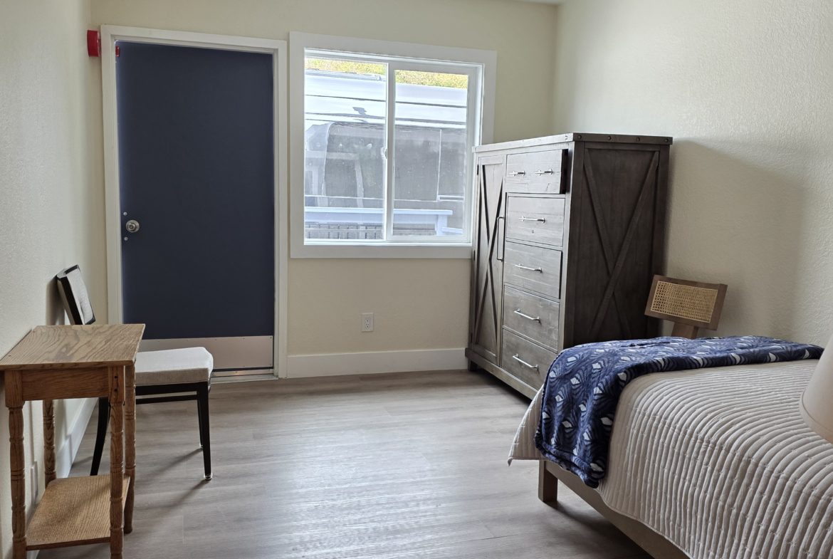 Simple bedroom with bed and wooden furniture.