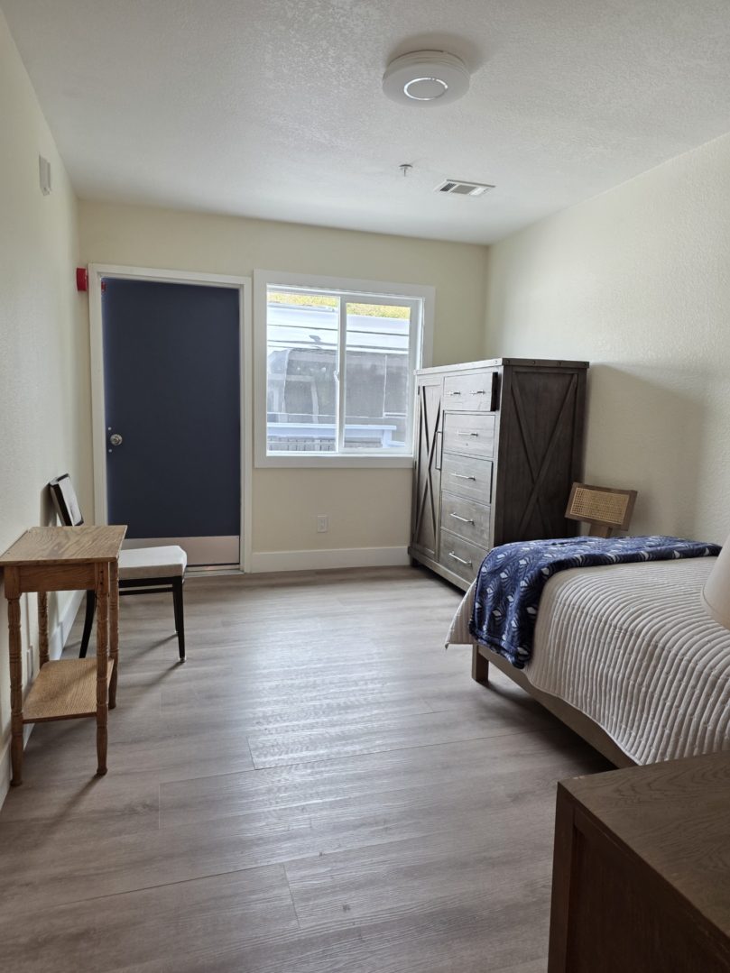 Simple bedroom with bed and wooden furniture.