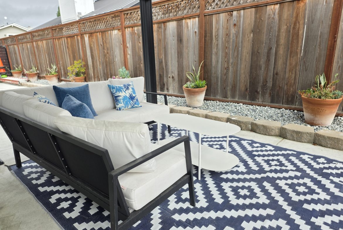 Outdoor patio with couch and decorative pillows.