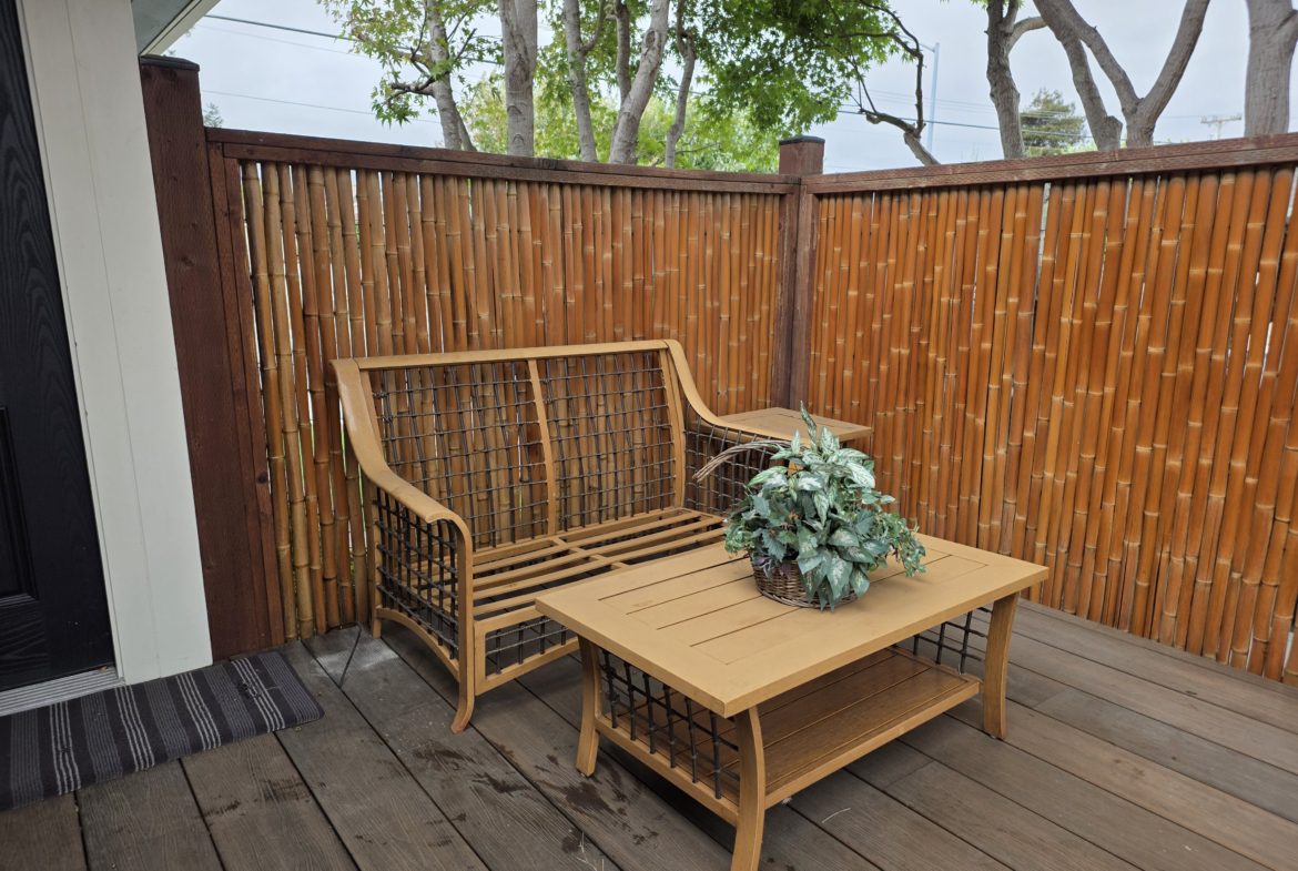 Outdoor patio with wooden furniture and plants.