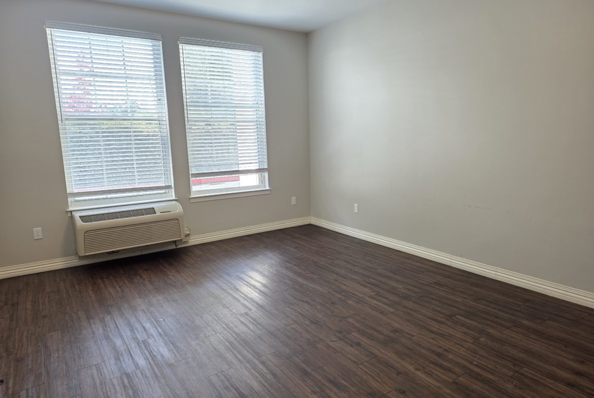 Empty room with wooden floor and windows.