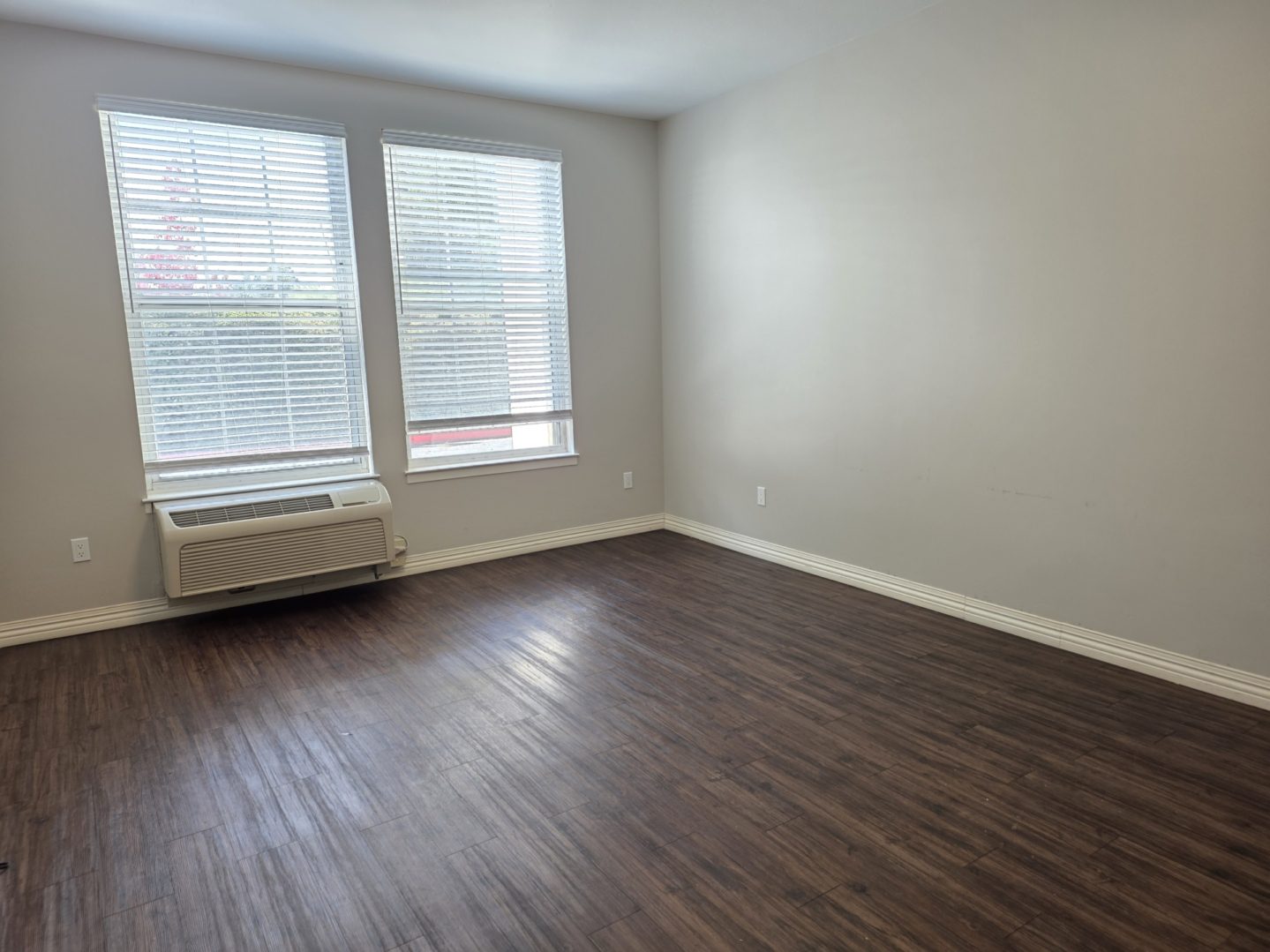 Empty room with wooden floor and windows.