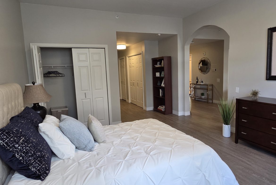 Modern bedroom with white bedding and closet.