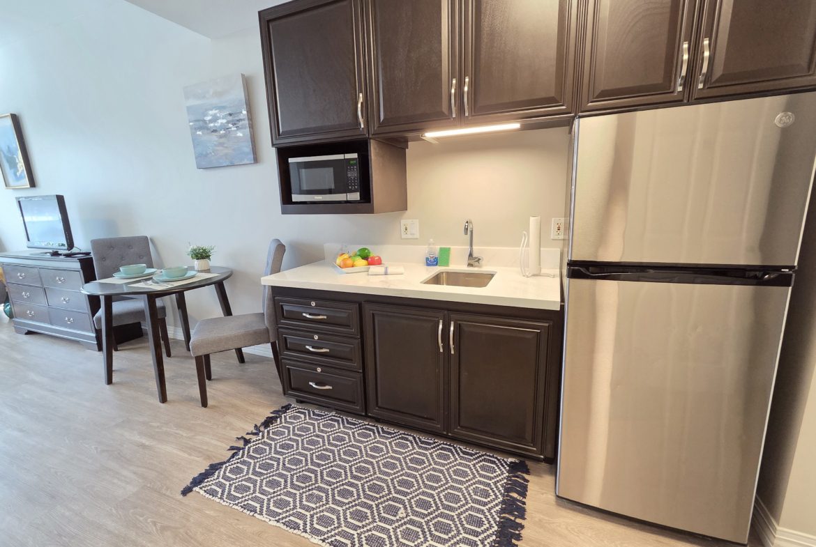 Small kitchen with dark cabinets and fridge.