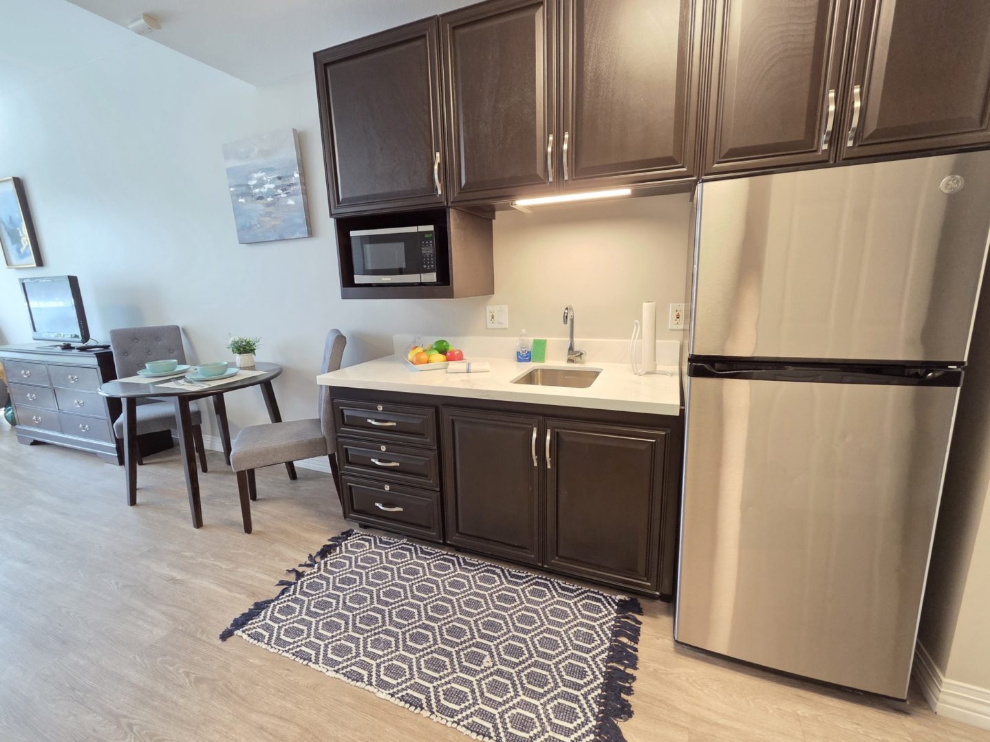 Small kitchen with dark cabinets and fridge.