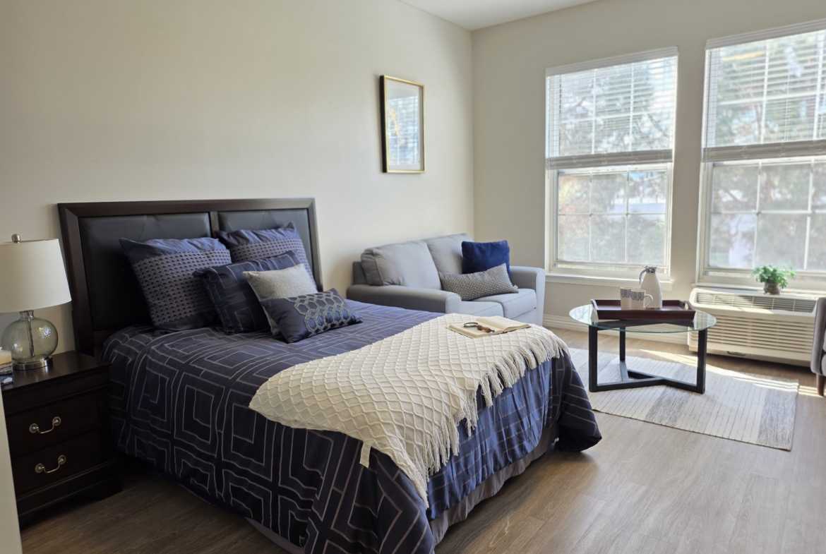 Modern bedroom with bed, sofa, and window.