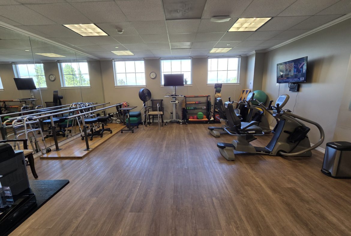 Rehabilitation gym with exercise equipment and mirrors.